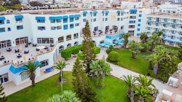 Un hotel de varios pisos con un patio central, zonas de estar al aire libre y una piscina.
