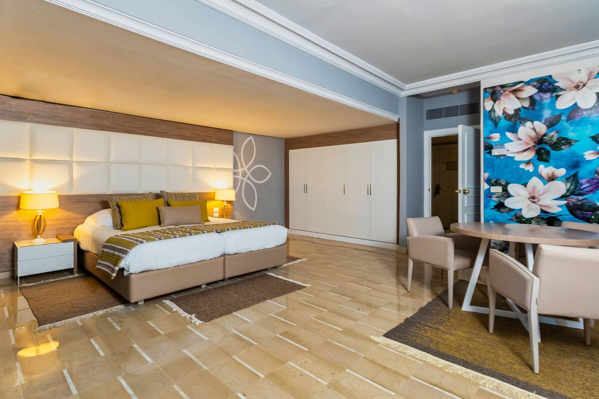 Une chambre à coucher moderne avec un lit, des tables de chevet, une table et des chaises.
