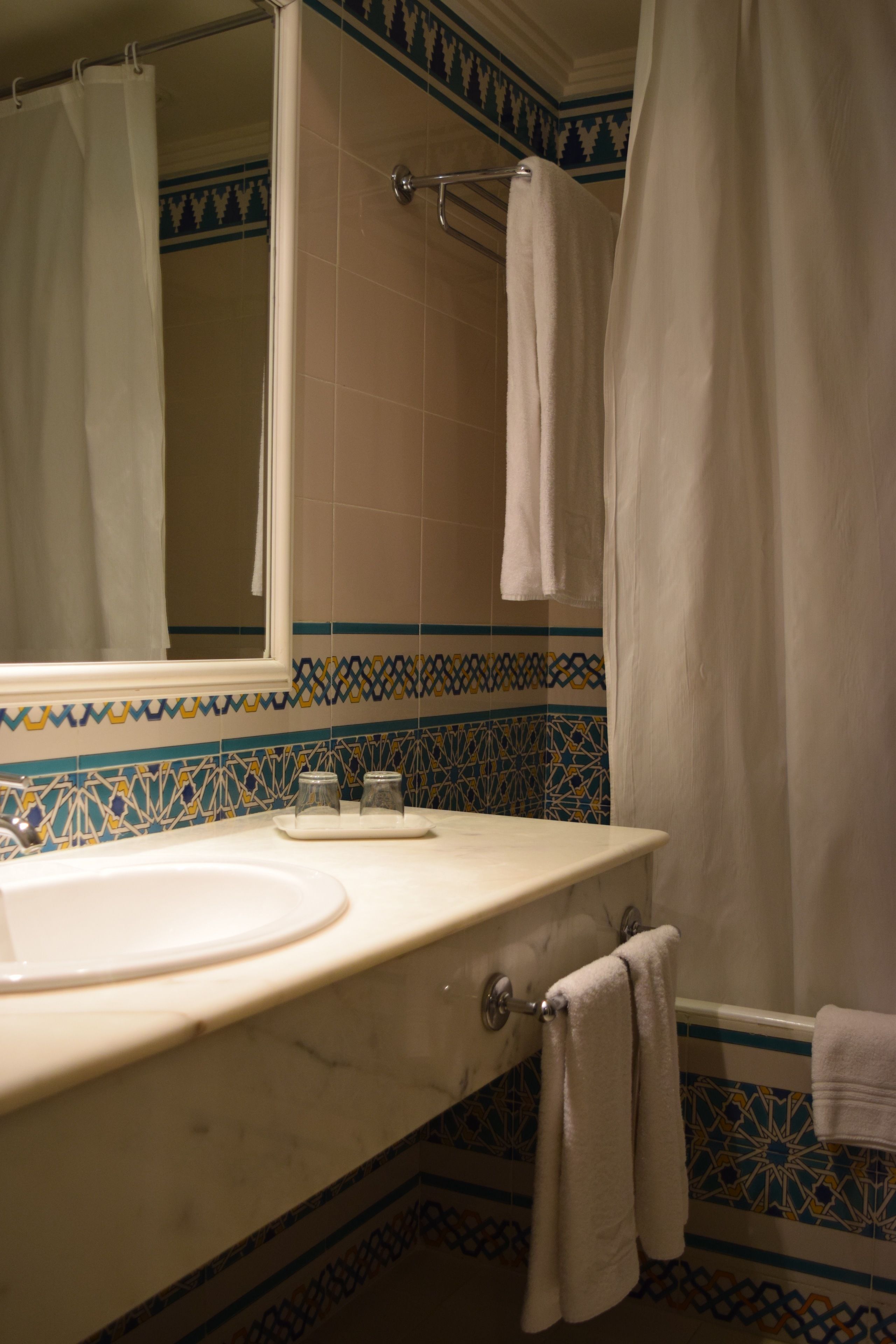 Un baño con lavamanos blanco, un espejo y una cortina de ducha.
