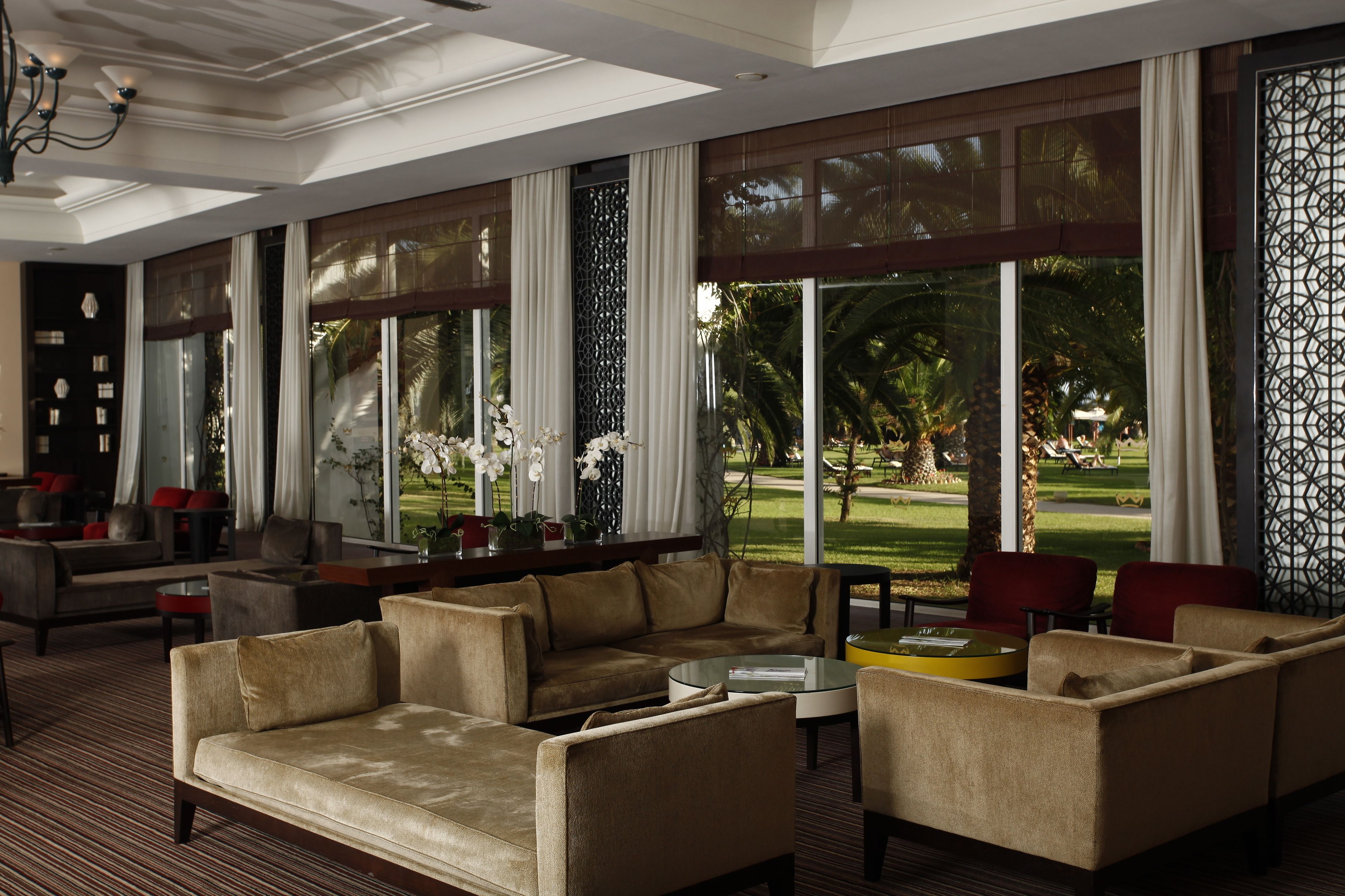 Ein geräumiger Wohnbereich mit einer großen Couch, Sesseln und einem Couchtisch. Große Fenster bieten Blick auf einen Golfplatz.