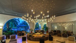 A spacious lobby with a large seating area, a water feature, and a view of a tropical-themed mural.