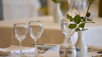 A table set with two wine glasses, a vase with a rose, and salt and pepper shakers.