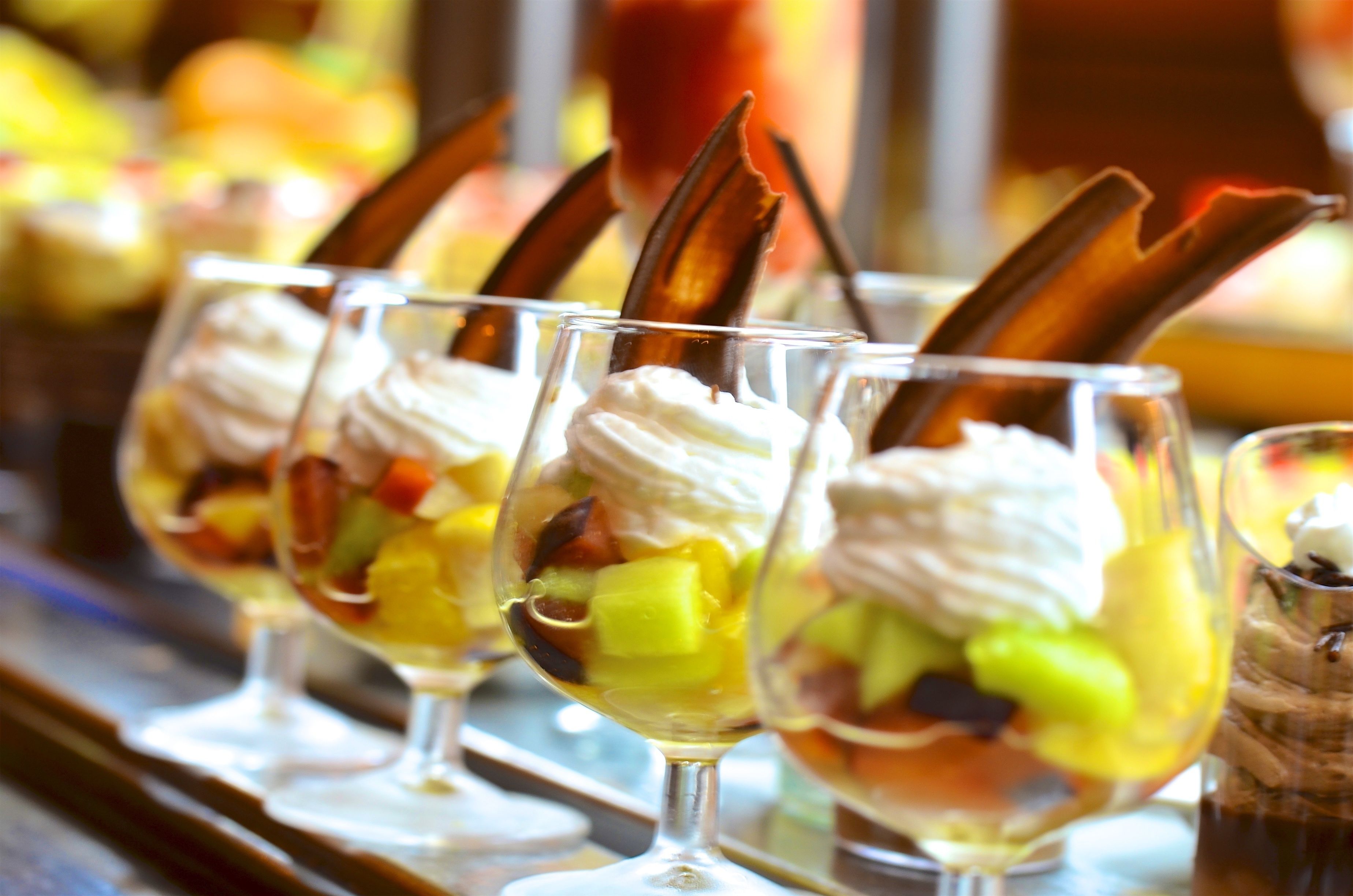 A dessert bar with various ice cream sundaes in glasses.