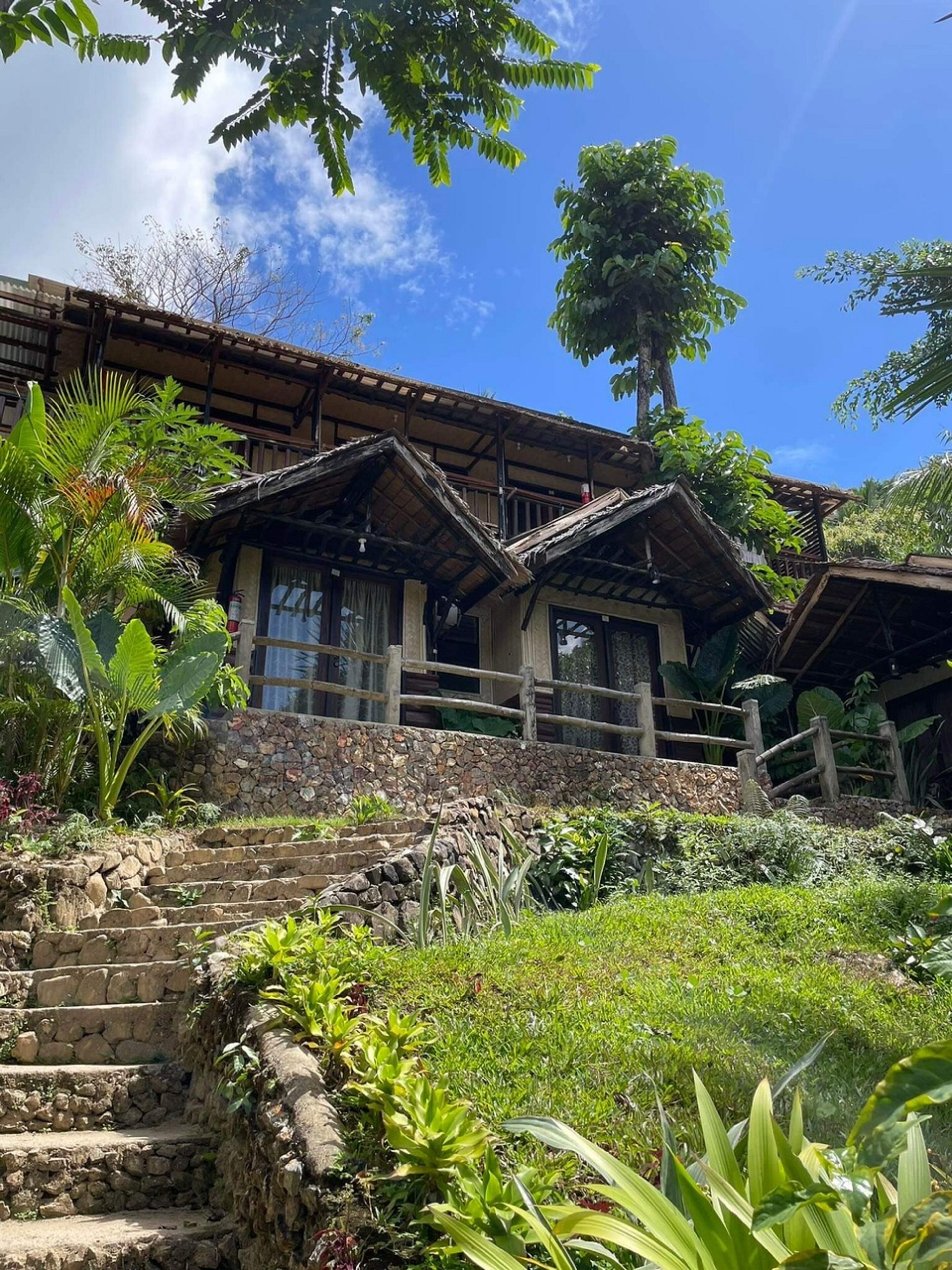Un edificio de madera tradicional con una escalera de piedra que sube a un porche.