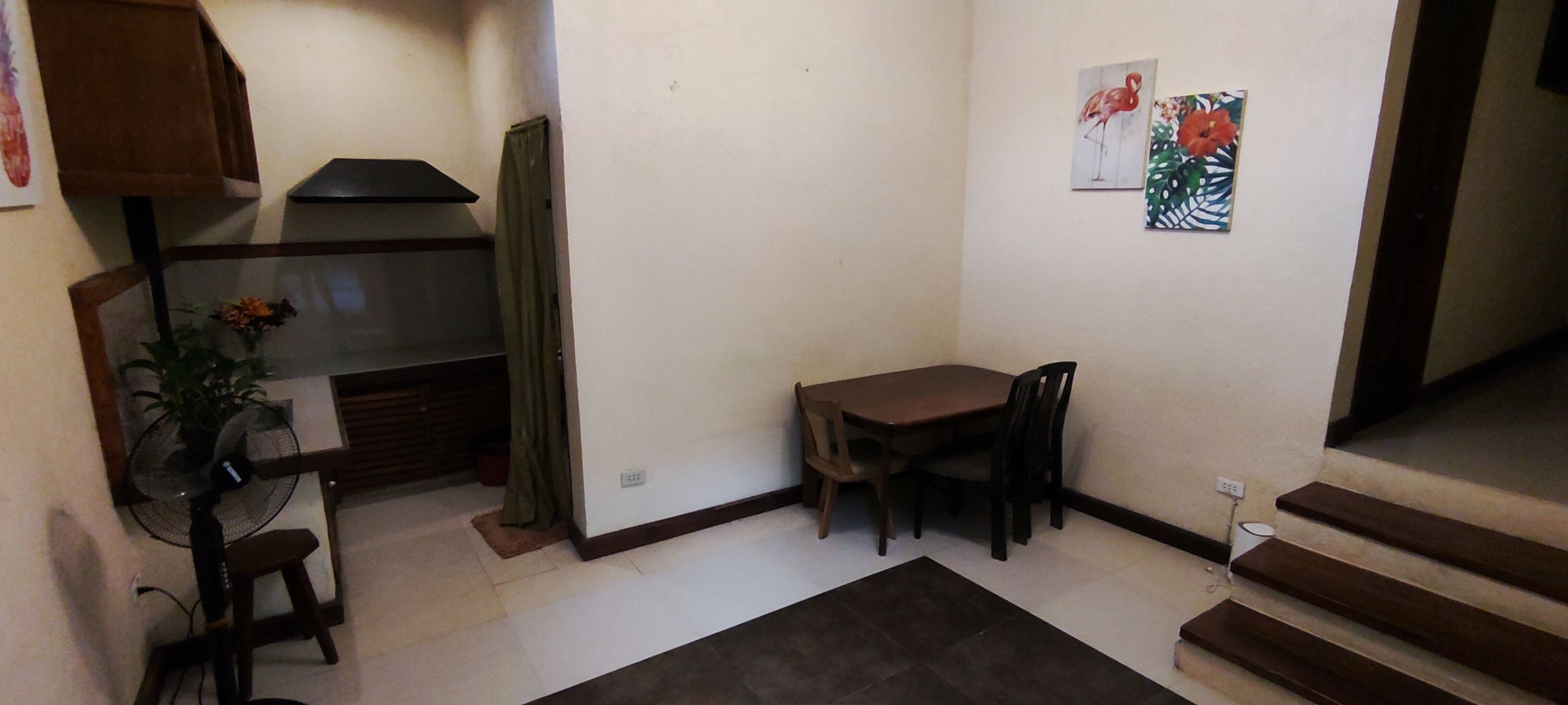 A small dining area with a table and chairs, a fan, and a potted plant.