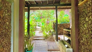 Un pasaje cubierto con paredes de piedra, plantas en macetas y vistas a un jardín exuberante.
