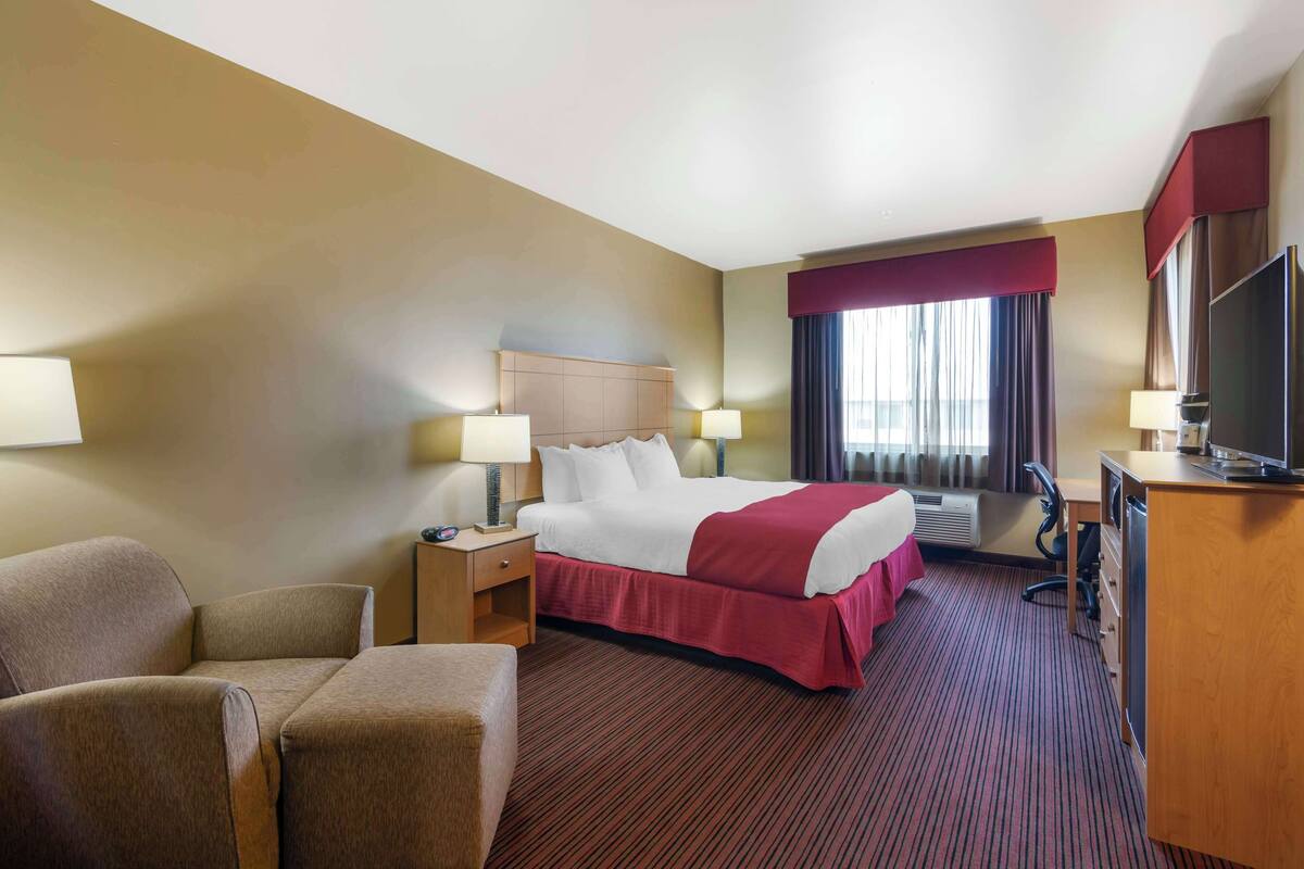 Ein Hotelzimmer mit Bett, Schreibtisch, Stuhl und Fernseher.