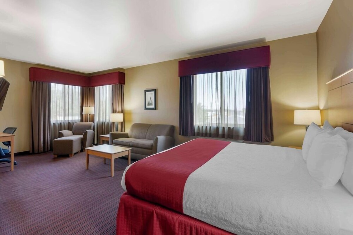 A hotel room with a large bed, two armchairs, a sofa, a small table, and a desk.