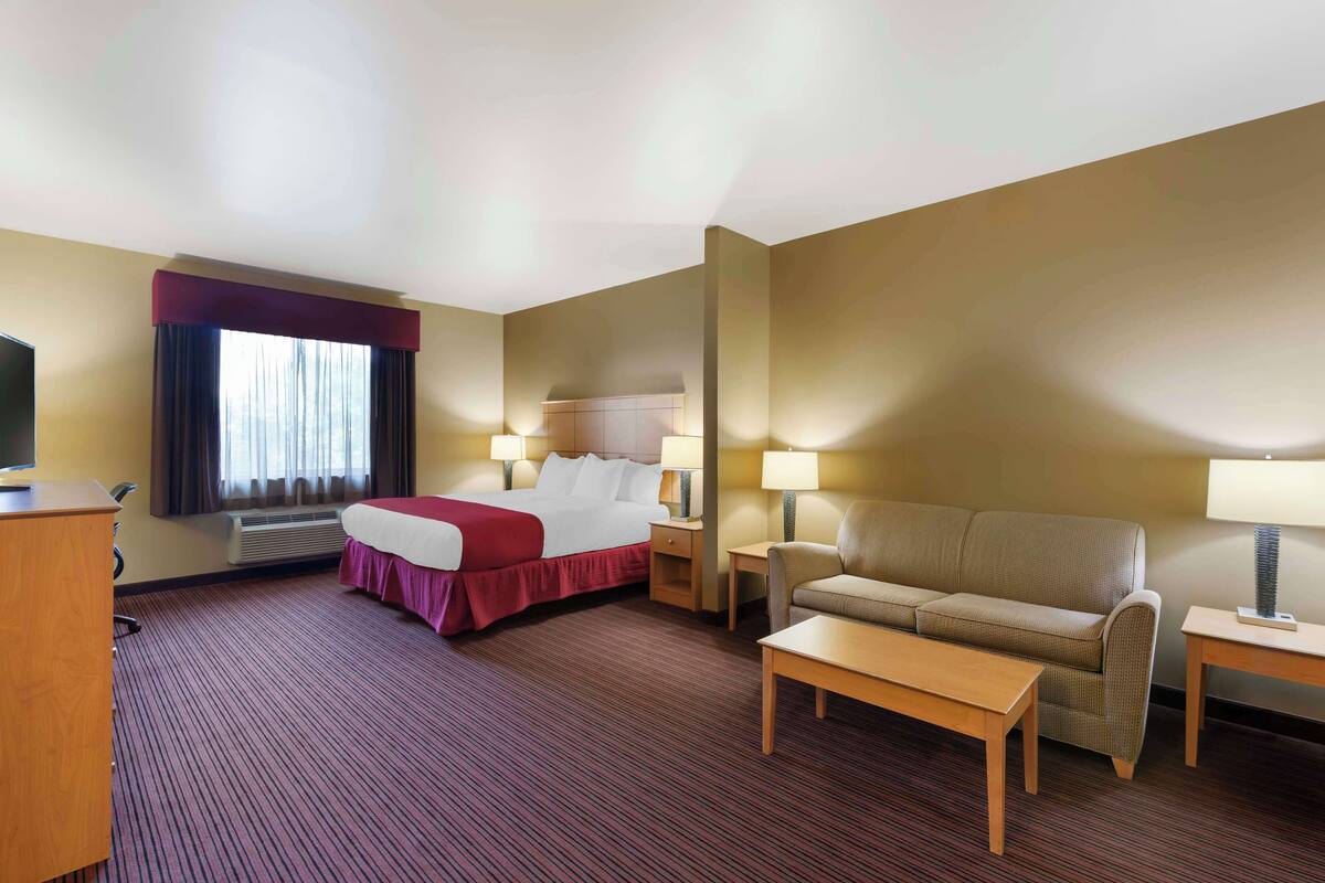 Ein Hotelzimmer mit Bett, Sofa, Schreibtisch und Fernseher.