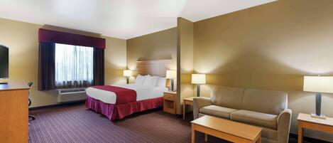 A hotel room with a bed, a sofa, a desk, and a TV.