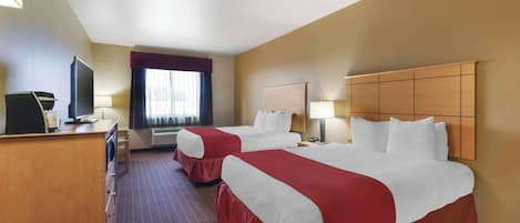 A hotel room with two beds, a desk, a television, and a window with curtains.