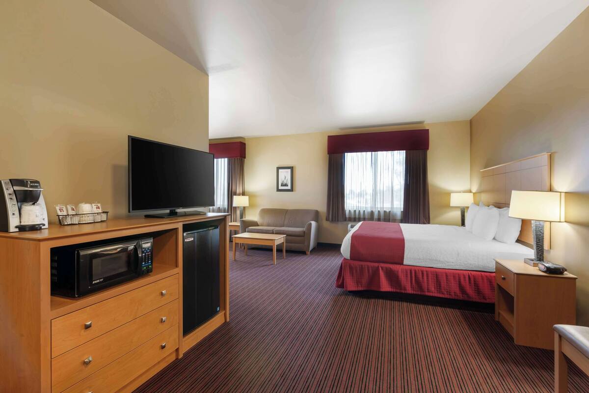Ein Hotelzimmer mit einem Bett, einem Fernseher, einer Mikrowelle, einer Kaffeemaschine, einem Schreibtisch und einem Stuhl.