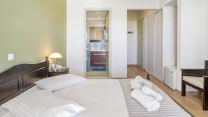 A hotel room with a large bed, a bedside lamp, a chair, and a view of the bathroom and closet. - Vergina Star (Lefkada)