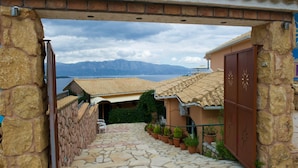 A stone-paved courtyard with a view of mountains and a lake. - Vergina Star (Lefkada)