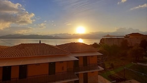 A coastal view with a sunset, buildings with tiled roofs, and a body of water. - Vergina Star (Lefkada)