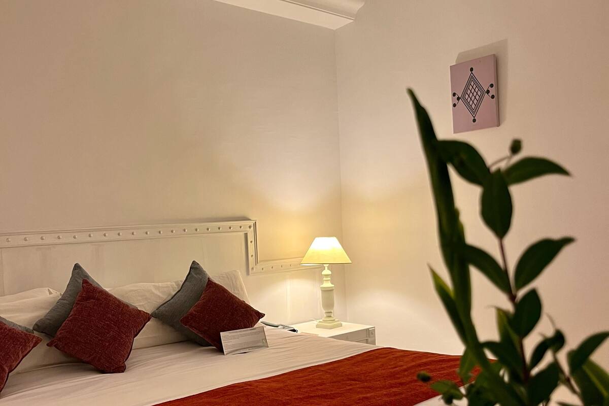 Ein Hotelzimmer mit einem Bett, Kissen, einem Nachttisch mit Lampe und einem Wandbild.