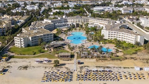 An aerial view of a resort with a central pool, multiple buildings, and a beach area with sun loungers. - hôtel Sentido Marillia Resort & Spa (Hammamet)