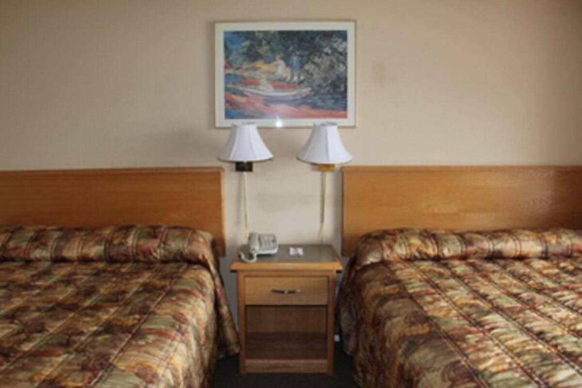 Une chambre d’hôtel avec deux lits, une table de chevet avec un téléphone et un tableau au mur.