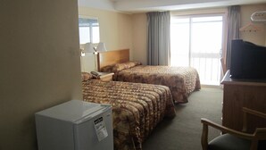 Een hotelkamer met twee bedden, een bureau, een televisie en een koelkast.