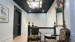 A hallway with two ornate chairs, a mirror, and a door. - Hotel Le Château de Pierre (Québec City)