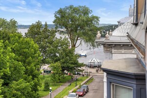 Une vue d’un parc avec un grand arbre, un kiosque et une rivière en arrière-plan.
