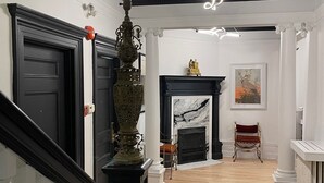A grand hallway with a staircase, a fireplace, and a large ornate lamp. - Hotel Le Château de Pierre (Québec City)