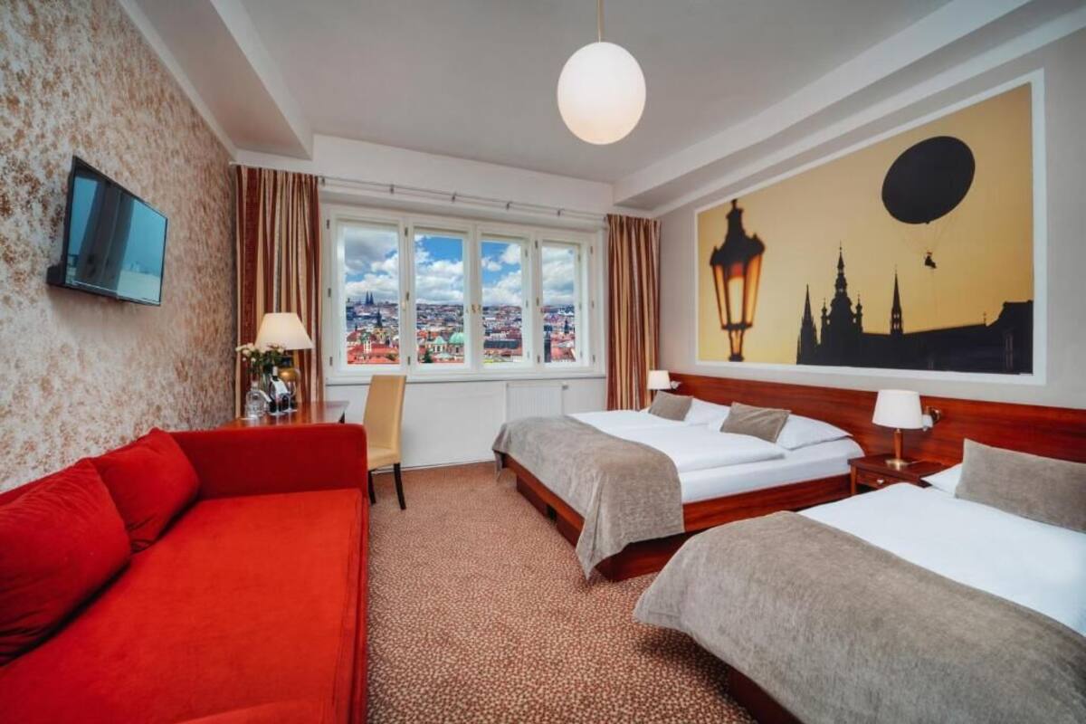 Een hotelkamer met twee bedden, een rode bank, een televisie en een stadsgezicht muurschildering.