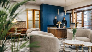 Un hall d’hôtel moderne avec un comptoir d’accueil, un espace salon et de grandes fenêtres.