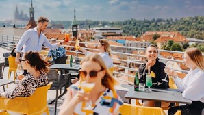 Un bar situé sur le toit, avec une terrasse, un barman et une vue sur les toits de la ville.