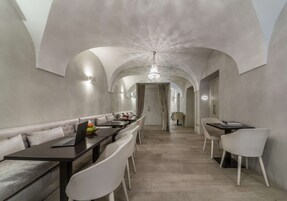 Zona pranzo moderna con un tavolo lungo, sedie bianche e un lampadario.
