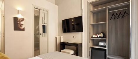 Une chambre d’hôtel équipée d’un lit, d’un bureau, d’une télévision, d’une armoire et d’un porte-manteau.