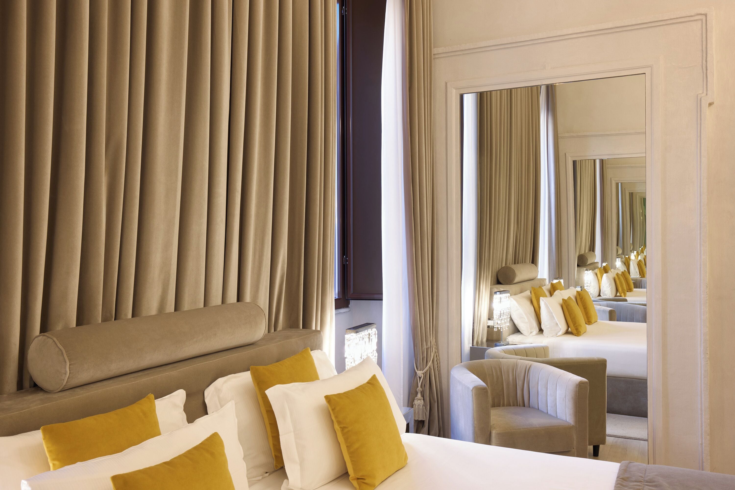 Una habitación de hotel con una cama grande, un sofá, una silla y un espejo que refleja el cuarto.