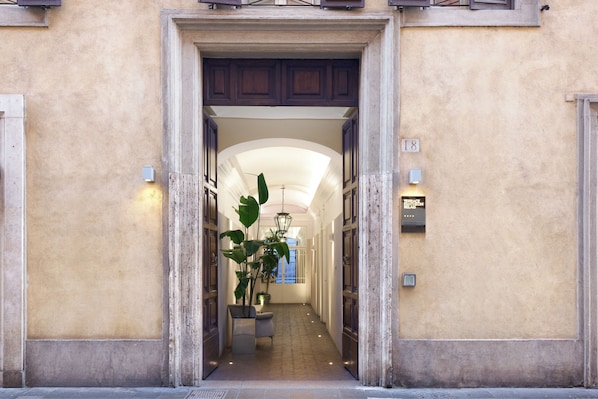 L’entrée d’un hôtel, avec une arche centrale, un pot de fleurs et un panneau indiquant l’emplacement.