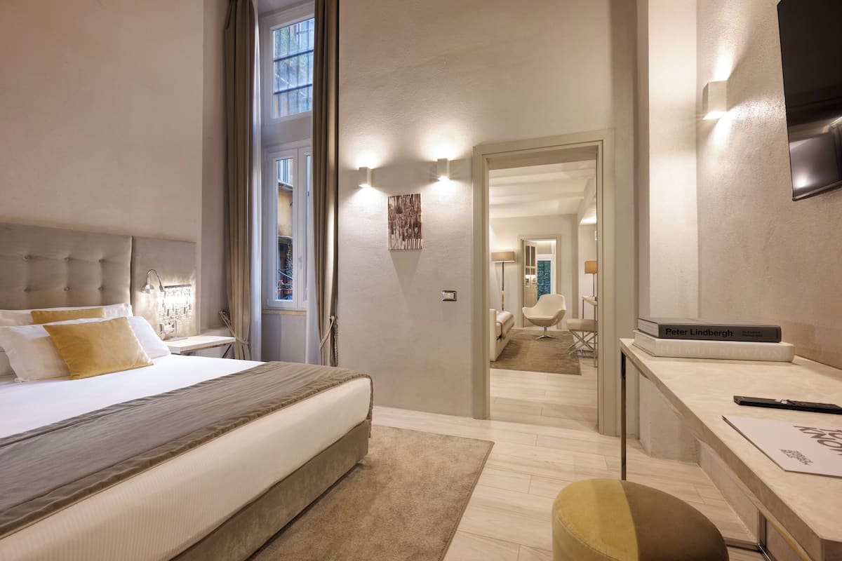 Et moderne hotelværelse med en stor seng, et skrivebord og udsigt gennem en åben dør.