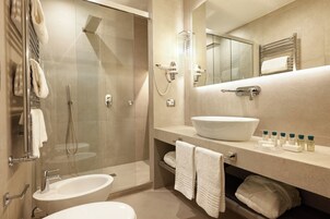 Un bagno moderno con doccia in vetro, un lavandino bianco grande e un mobile con articoli da toilette.