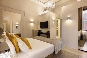 Una moderna camera d'hotel con un letto grande, una televisione a schermo piatto montata a parete, una scrivania con una sedia e un lampadario.