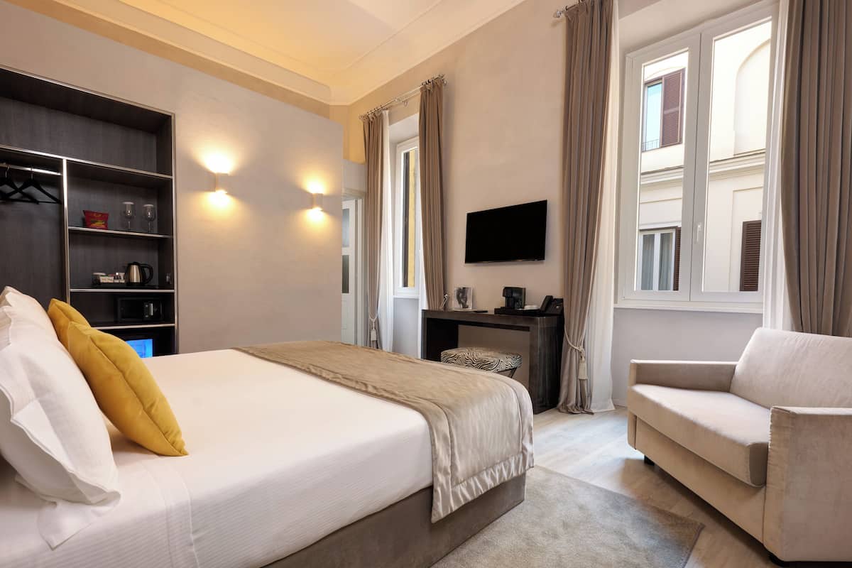 Et hotelværelse med seng, sofa, skrivebord og fjernsyn.