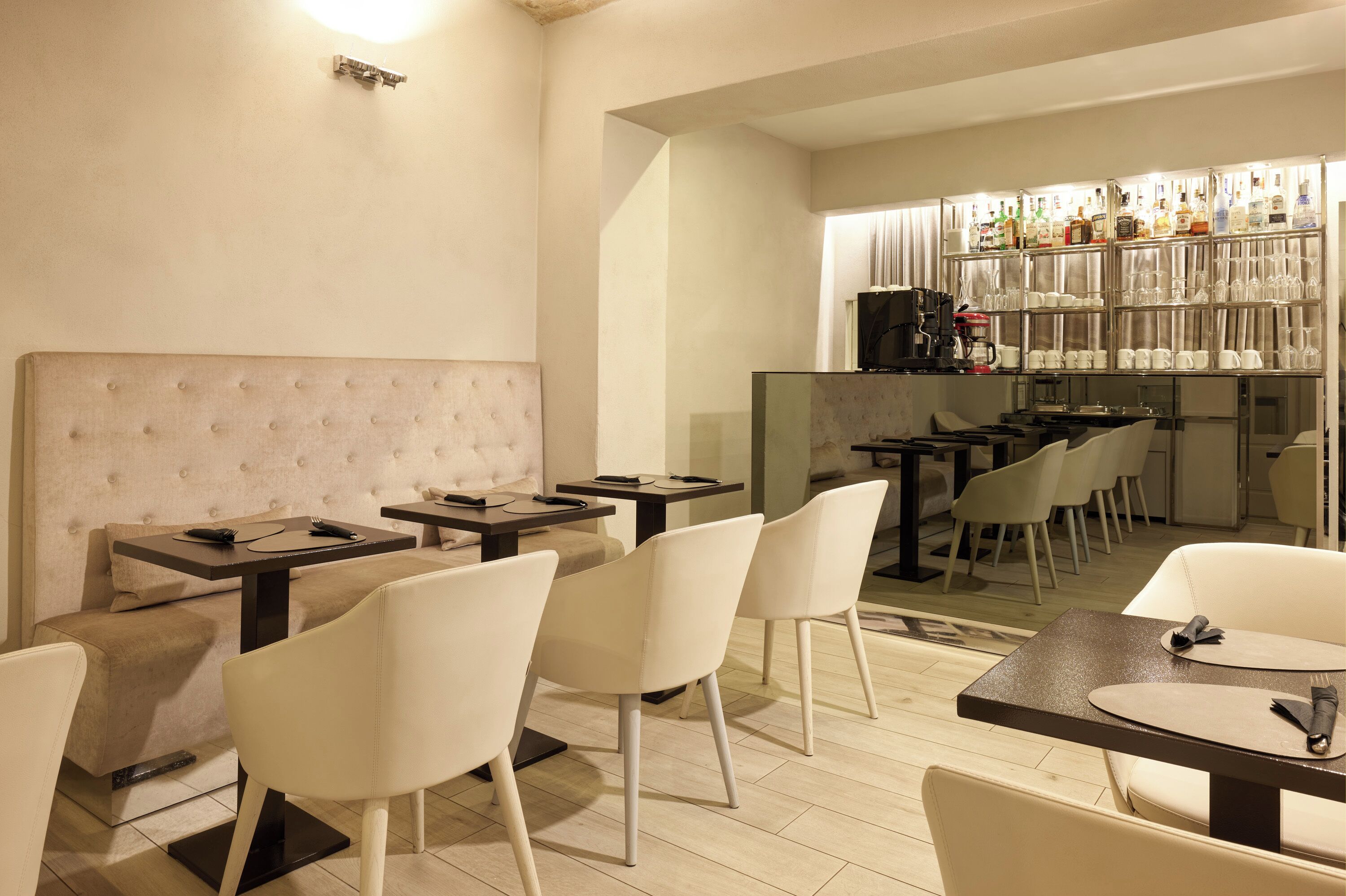 Un restaurante moderno con zona de bar, que ofrece una combinación de mesas para comer y asientos de bar, y una paleta de colores neutros.
