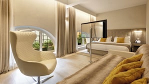 A modern hotel room with a large bed, a curved armchair, a flat-screen TV, and a view of greenery through large windows. - Terrace Pantheon Relais (Rome)