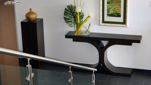 A modern reception area with a reception desk, a framed artwork, and a potted plant.
