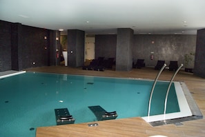An indoor swimming pool with lounge chairs and a wooden deck. - Villa Pampilhosa Hotel (Pampilhosa da Serra)