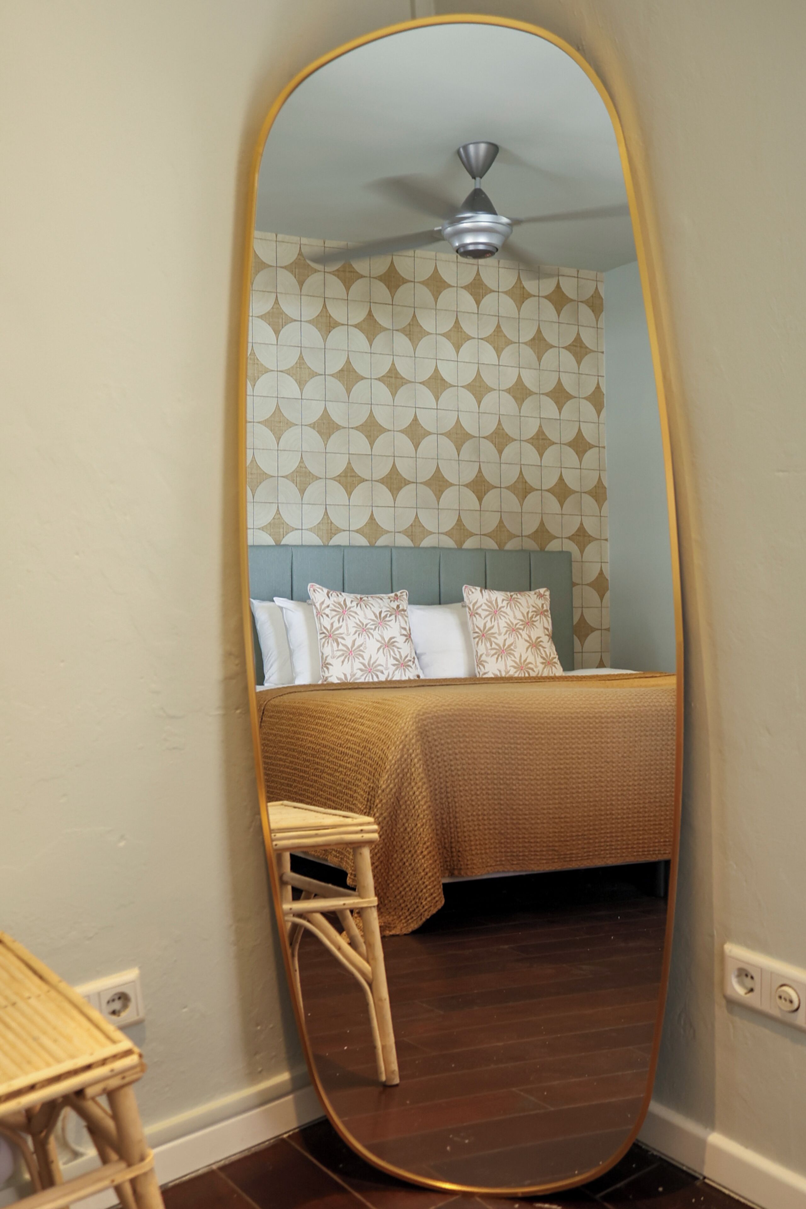 Une chambre à coucher avec un lit, un ventilateur de plafond et un papier peint à motifs.
