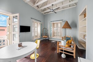 Una habitación con una mesa de comedor, sillas, una silla colgante, un televisor y un ventilador de techo.