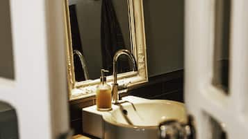 Un baño con un lavabo blanco, un espejo con marco dorado y una encimera de madera.