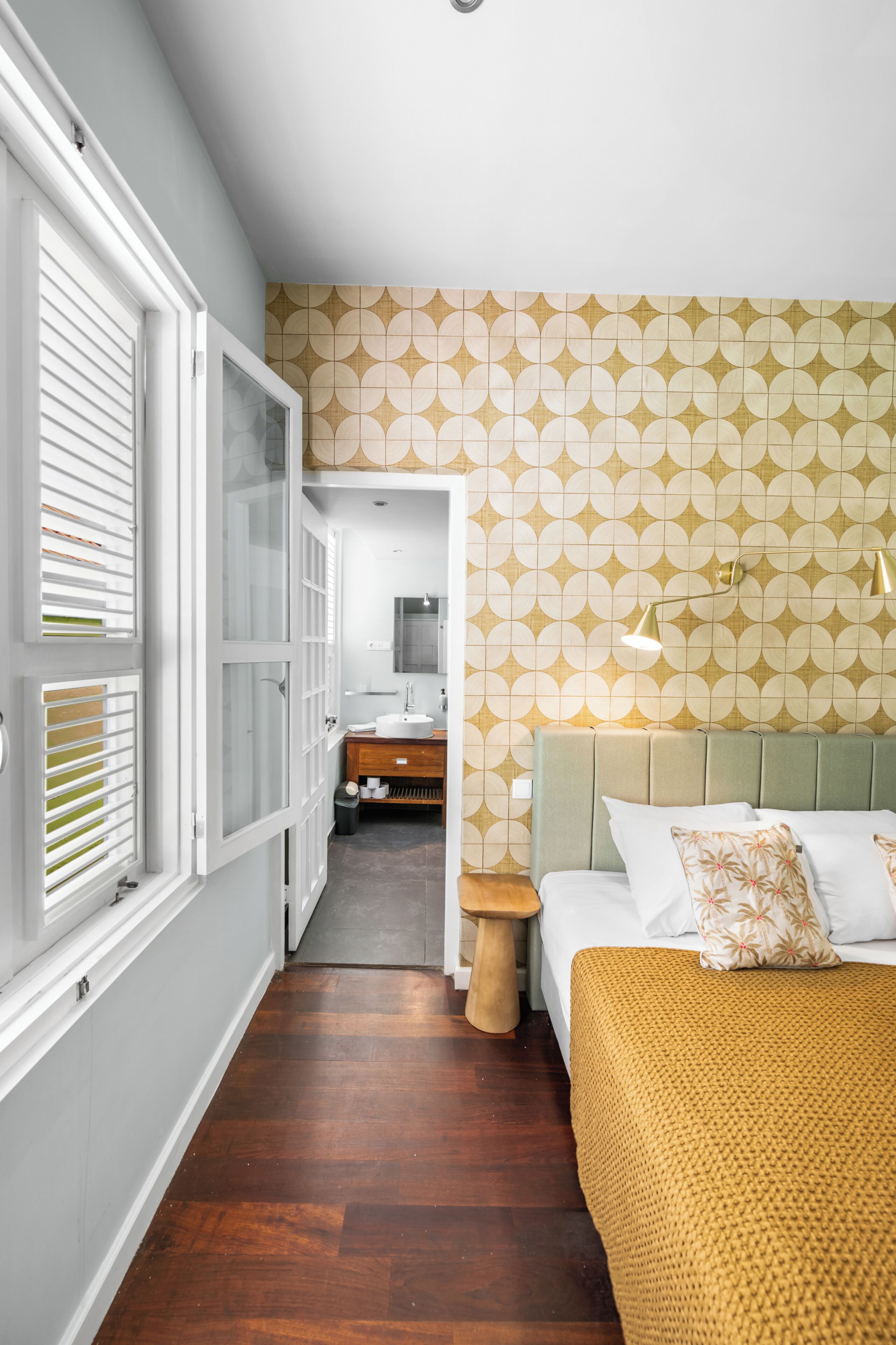 A bedroom with a bed, bedside table, and a bathroom visible through an open door.