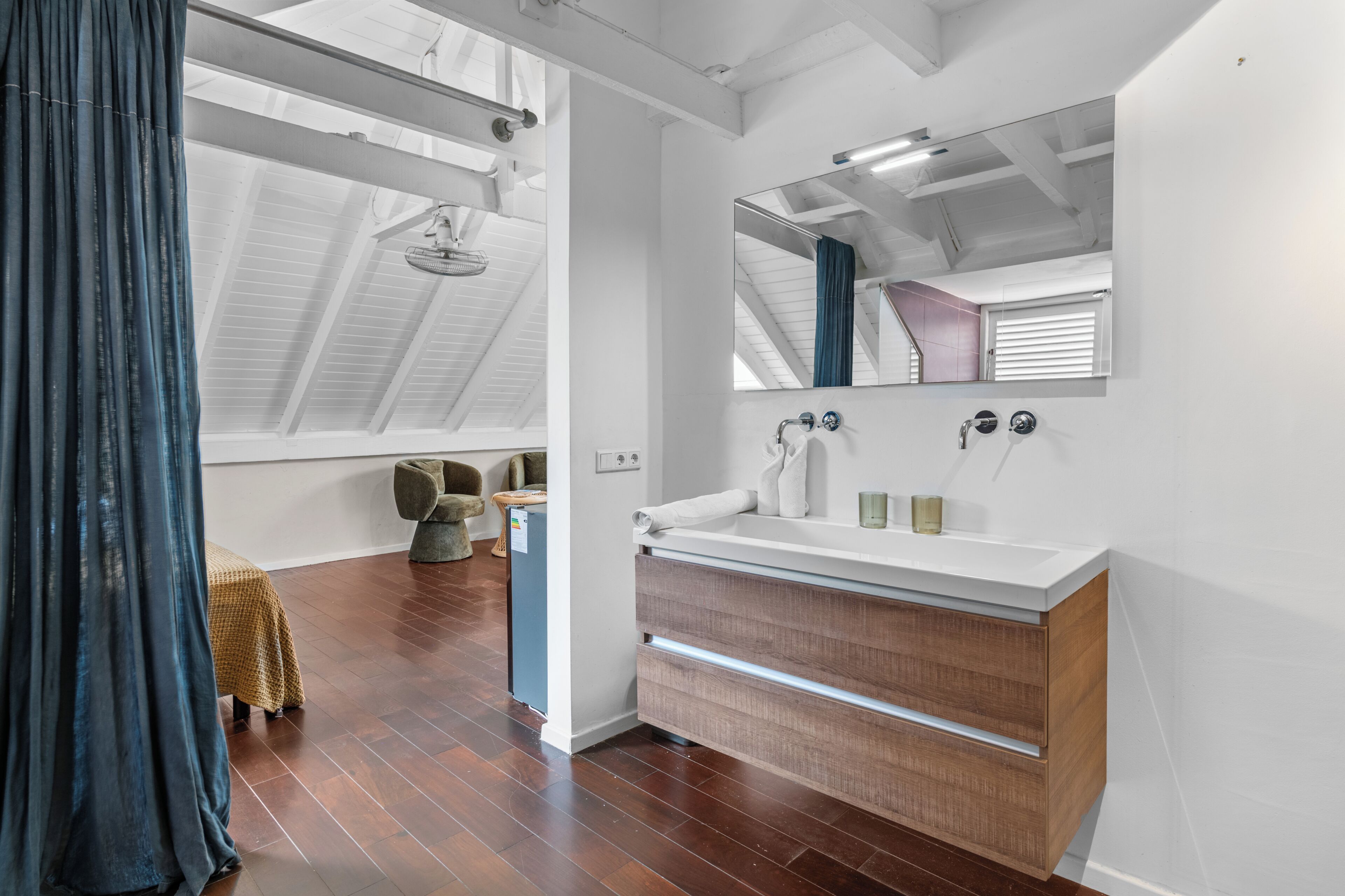 Een moderne badkamer met een grote spiegel, een houten wastafelmeubel en een plafondventilator.