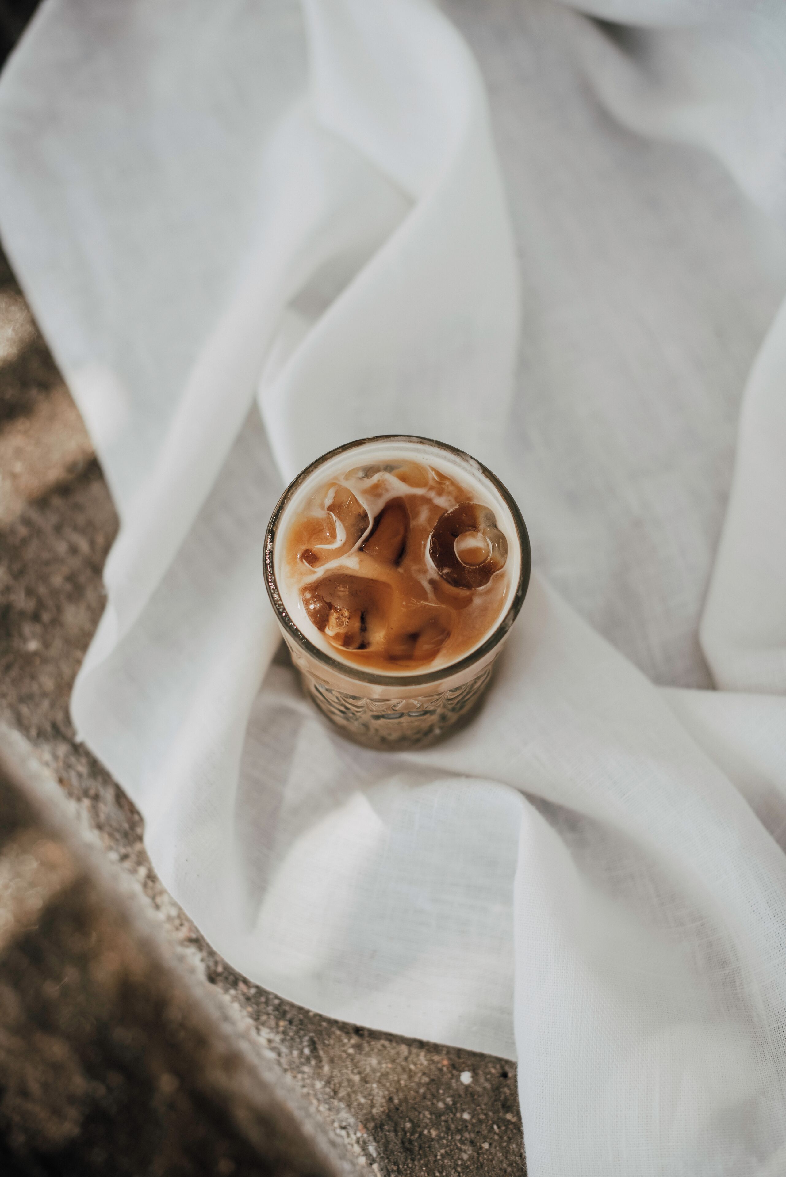 Un verre de café glacé posé sur un tissu blanc.