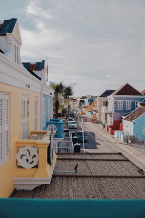 A street with colorful buildings, a wooden boardwalk, and parked cars.