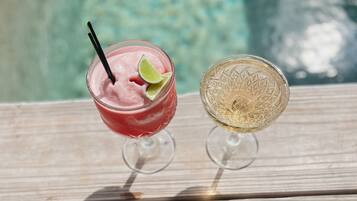 Deux boissons sur une terrasse en bois, près d’une piscine.