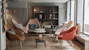 A modern living room with multiple seating options, a coffee table, and a bookshelf.